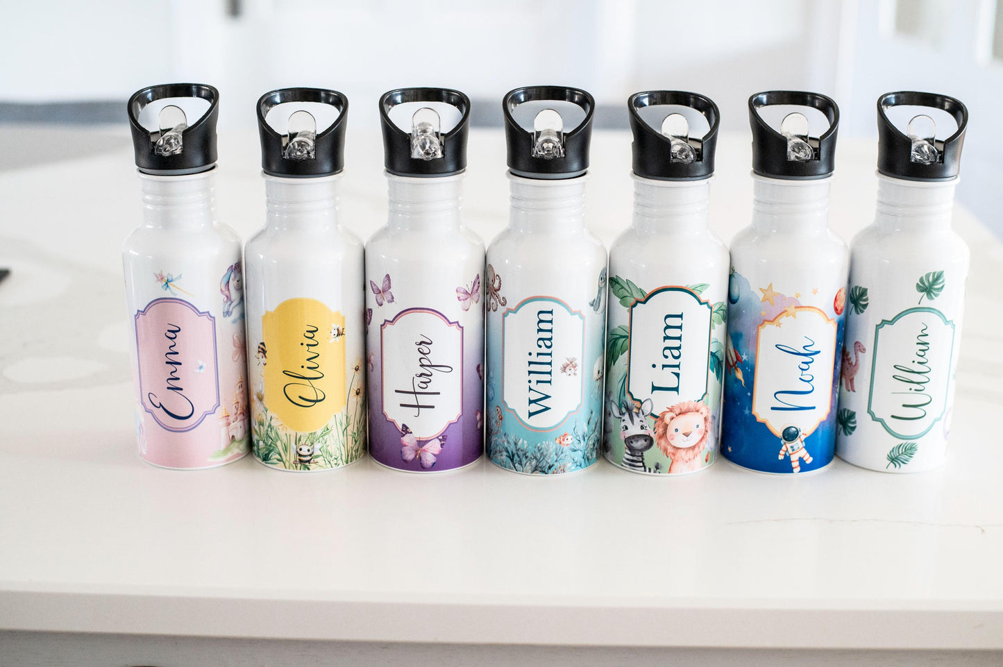 Set of personalized water bottles with different designs and names on a white surface.