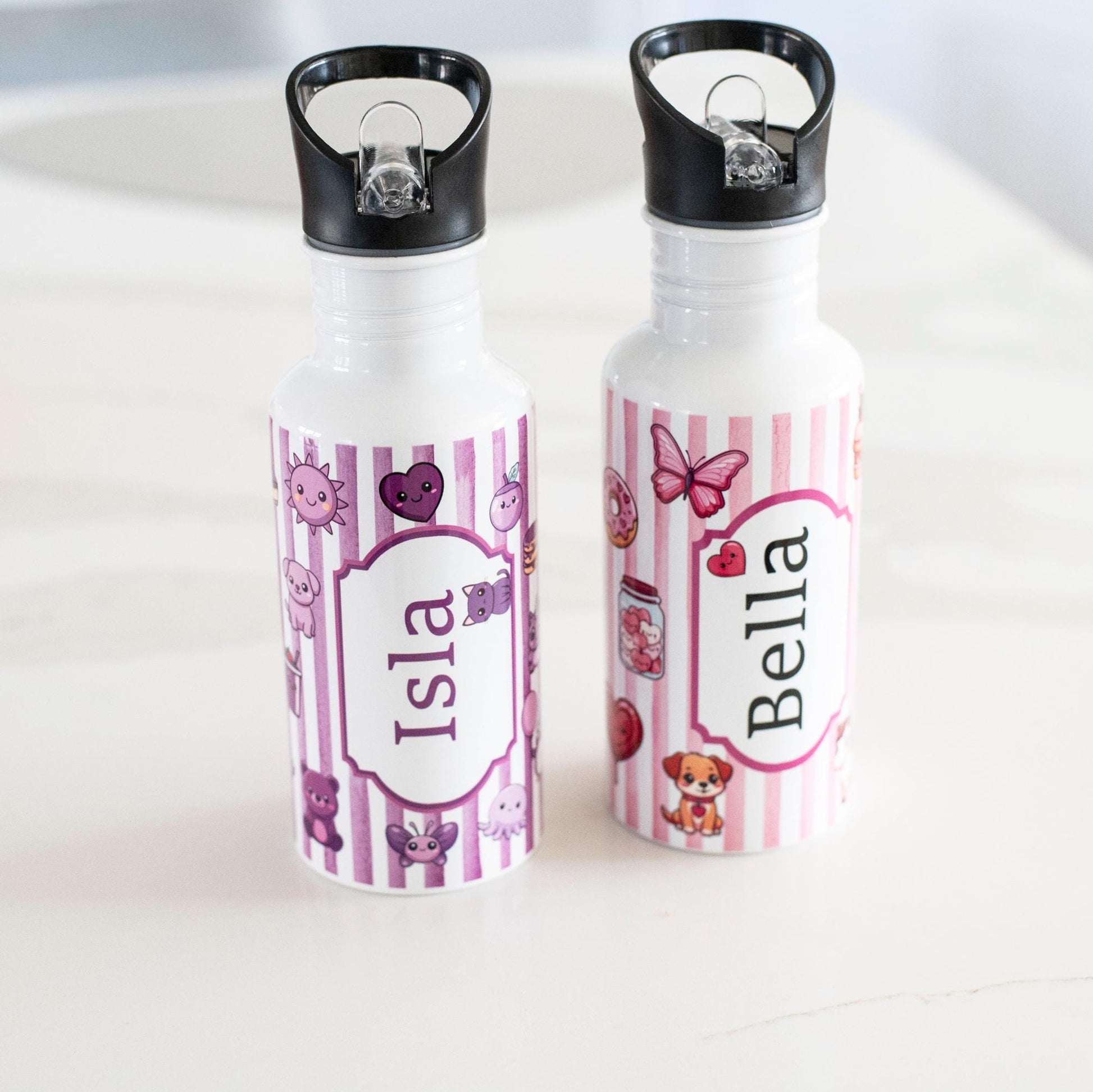 Two personalized water bottles with names 'Isla' and 'Bella' on a white surface.